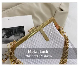 Detail der weißen Abendtasche mit glänzender Schuppentextur und goldenem Metallverschluss