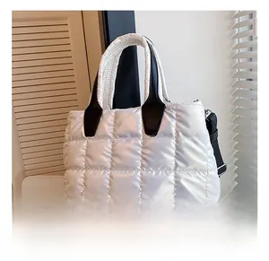 Detail showing the white quilted puffer texture and black leather handles of the tote bag