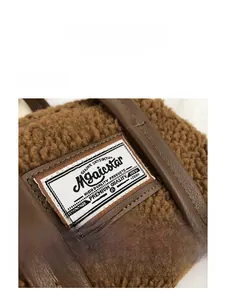 Close-up of brown faux shearling bag with leather handle and woven brand label