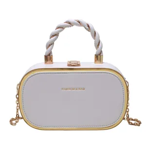 Witte doosvormige crossbodytas met gouden hardware en gedraaid handvat voor zomerse mode