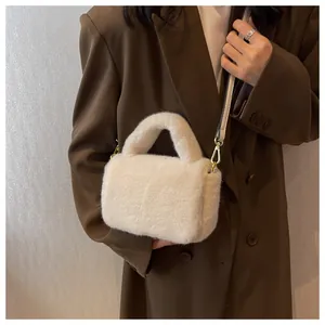 Gros plan d'un sac à main en peluche crème avec des détails en métal doré élégant