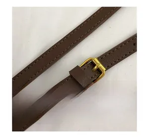 Close-up of the golden hardware buckle and brown leather strap with fine stitching details