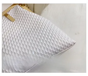 Detailansicht der weißen Handtasche mit hochwertiger Wabenstruktur und goldenem Verschluss