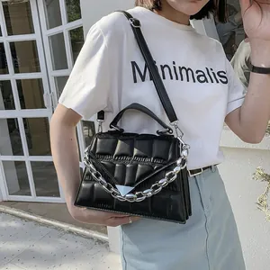 Close-up of black quilted leather crossbody bag with silver chain and metal clasp detail