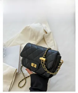 Detail of black quilted shoulder bag with gold metal twist lock and chain strap on desk