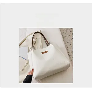 Dettaglio della borsa tote trapuntata bianco crema con manici marroni su sfondo lifestyle