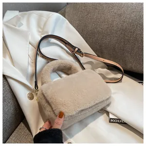 Détails de la texture pelucheuse en fausse fourrure et boucles dorées du sac beige