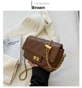 Detail view of brown quilted crossbody bag with gold chain strap on white blazer