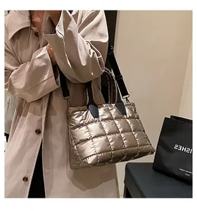 Close-up of champagne gold quilted tote bag with black handles and metal luster