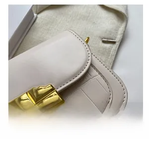 Close-up of minimalist cream white handbag with crocodile pattern and golden metal lock