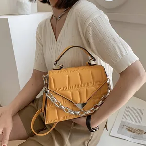 Detail of yellow pleated handbag with silver chain and metal buckle on white background