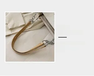 Dettaglio della tracolla in pelle beige e della catena in metallo argentato sulla borsa