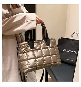 Detail of metallic gold quilted tote bag with black handles and metal link buckle