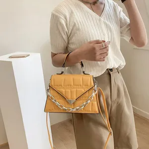 Detail of yellow quilted leather bag with silver chain and metal buckle on model
