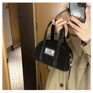 Detail of black faux shearling handbag with gold hardware and brand label on front
