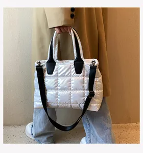 Detailed view of white quilted down tote bag with black leather handles and wide strap