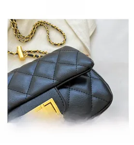 Close-up of black quilted leather bag with gold square twist lock and metal chain strap