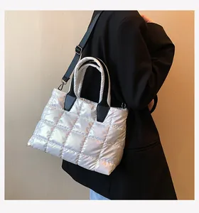 Detail of silver quilted tote bag with black handles and adjustable shoulder strap on model
