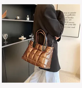 Detailed side view of metallic quilted down tote bag with leather handles on a model