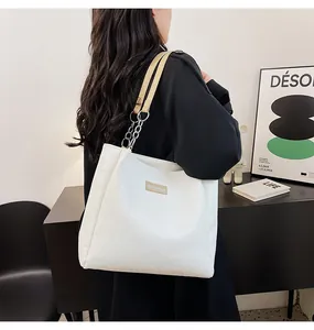 Dettaglio borsa tote trapuntata in pelle PU bianca con catena d'argento e placca logo in metallo