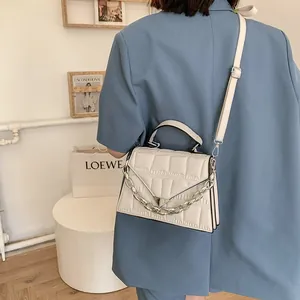 Detailed view of white crocodile pattern crossbody bag with silver chain and V-flap