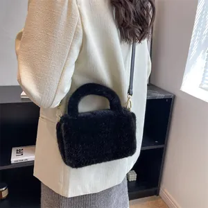 Sac bandoulière chic en fausse fourrure noire avec détails dorés porté par un mannequin