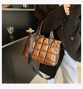 Detail of a brown quilted puffer tote bag with glossy finish and adjustable shoulder strap
