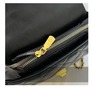 Detail showing high-quality gold metal zipper and stitching on black quilted leather bag