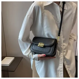 Detail showing black croc-embossed leather texture and gold square metal buckle on shoulder bag