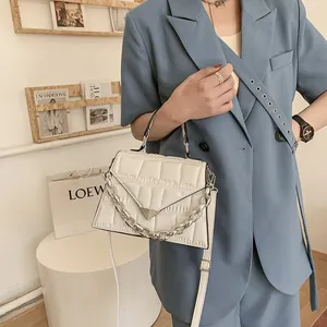 Detail of ivory faux crocodile texture bag featuring silver triangle lock and chain