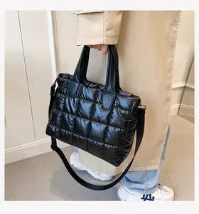 Detail of black quilted puffer tote bag with glossy finish and detachable shoulder strap