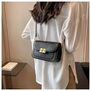 Detail of black crossbody bag featuring crocodile texture and golden square magnetic clasp