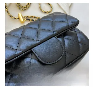 Detail of high-quality quilted leather texture and gold metal clasp on a black handbag