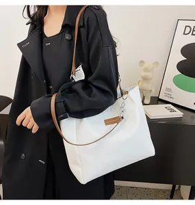 Dettaglio della borsa tote bianca trapuntata con manici in pelle marrone e catena