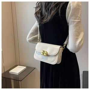 Detail of a creamy crossbody bag with crocodile texture and golden square lock on a model