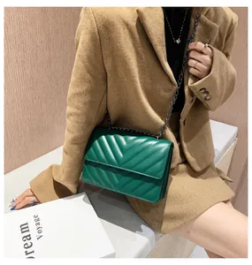 Detail of green quilted leather bag with V-shaped stitching and black metal chain strap