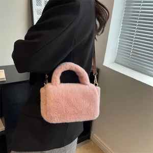 Sac à main en fausse fourrure rose avec poignée pelucheuse et bandoulière sur blazer noir