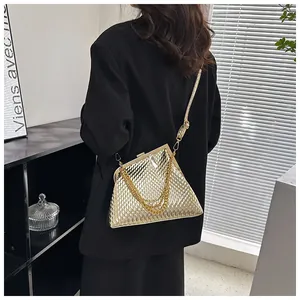 Detail der goldenen Abendtasche mit Metallschuppen und Kettenriemen auf schwarzem Blazer