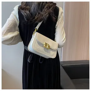 Detail of cream white crossbody bag with crocodile pattern and golden metal buckle clasp