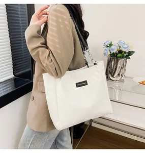 Dettaglio della borsa tote trapuntata bianca con catena e toppa logo in pelle