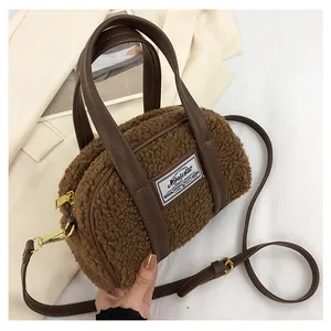 Detailed view of brown plush faux shearling handbag with leather handles and gold hardware