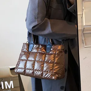 Quilted down puffer tote bag in metallic brown finish worn by model in studio