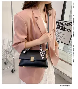 Détail d'un sac à bandoulière noir mat avec fermoir doré et décor de foulard en soie