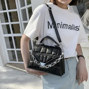 Quilted black crossbody bag with silver chain detail and adjustable strap on a model