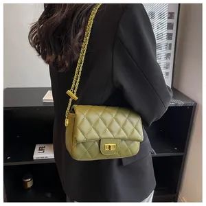 Detail of dark green quilted shoulder bag with gold twist lock and metal chain strap