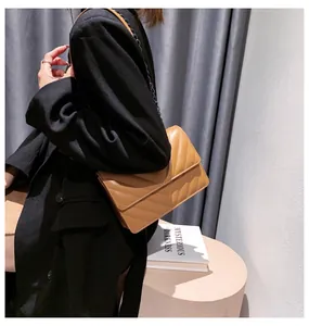Close-up of brown quilted crossbody bag with V-shaped stitching and black chain strap