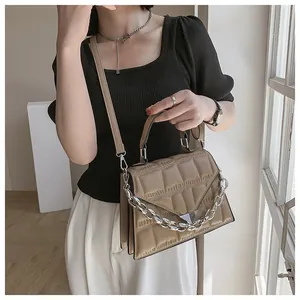 Khaki embossed crossbody bag with silver chain strap shown on a model in a minimal style