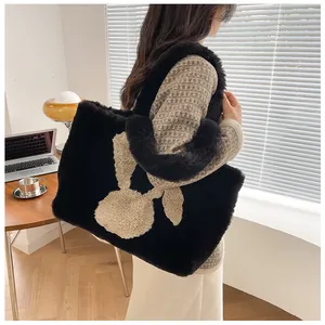 Detail of a large black faux fur tote bag with a beige rabbit motif in an indoor setting