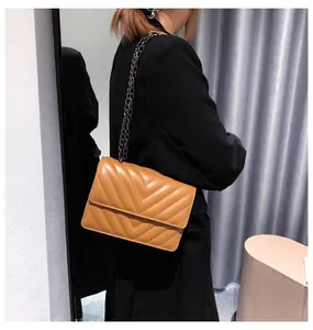 Brown quilted chain bag with V-shaped stitching shown as crossbody on model