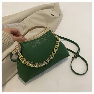 Detail van groene leren tas met gouden hardware en decoratieve ketting met juwelen